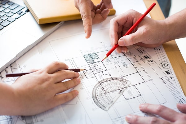 Permit drawing professionals reviewing commercial interior floor plan blueprints for a tenant fit-out project