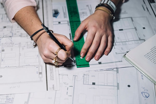Engineer using a compass on legal basement floor plan permit drawings for Ontario Building Code compliance